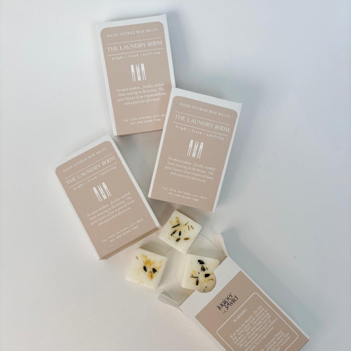 A few boxes of The Laundry Room wax melts from Juniper & Wild with some cubes coming out of a box