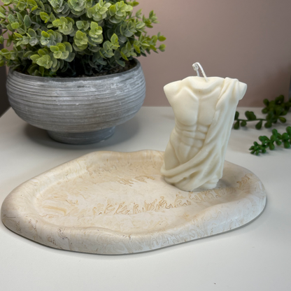 Eco-friendly stoneware candle holder with a plant in the background on a neutral surface.