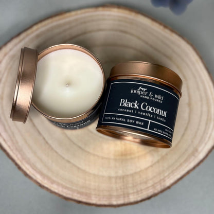 Candle in a tin with a visible label on a wooden surface