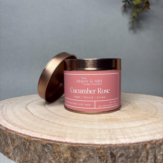 Candle with 'Cucumber Rose' label on a wooden surface against a gray background