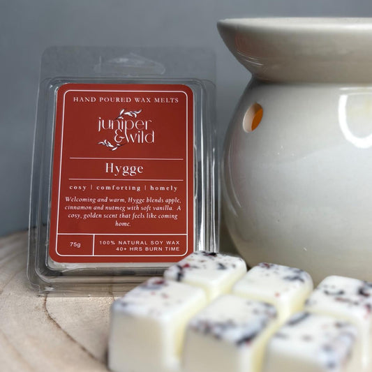 Hand poured wax melts packaging with 'juniper & Wild' branding and a wax warmer on a wooden surface.