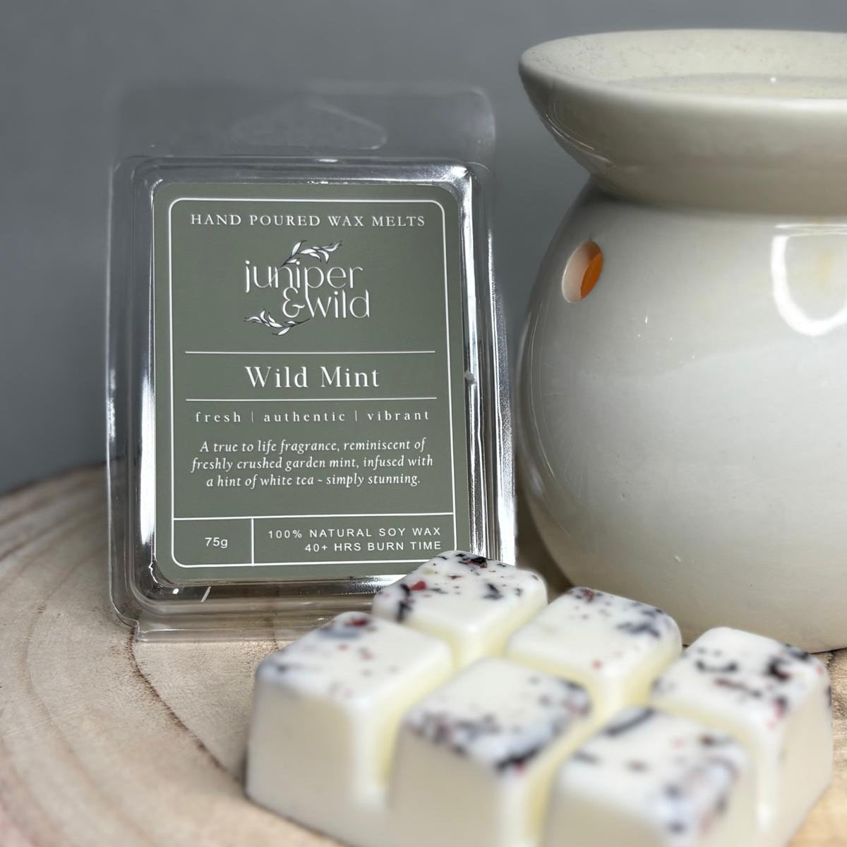 Hand-poured wax melts with packaging labeled 'juniper & wild' on a wooden surface.