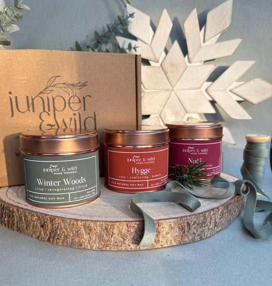 Collection of candles from juniper & wild on a wooden stand with decorative elements.