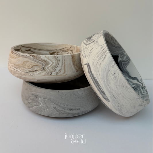 Marble-patterned ceramic bowls on a light gray background with 'juniper & wild' branding.